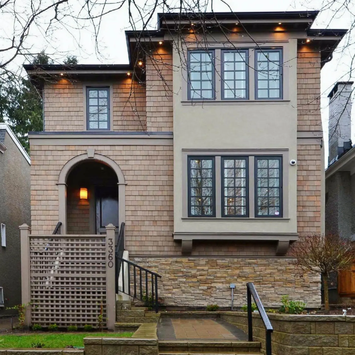 Two-storey house with shingle cladding and an arched front entrance