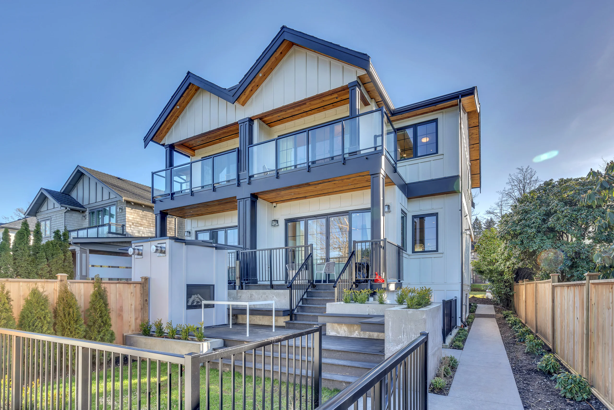 A new three-storey custom home with a wood-trimmed roofline and glass balconies