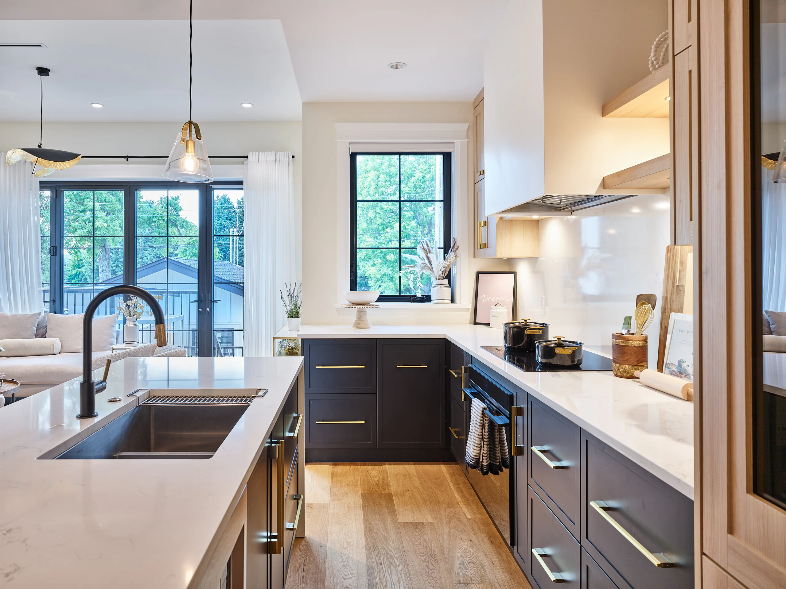A kitchen with navy cabinets, white stone counters and a window over the sink