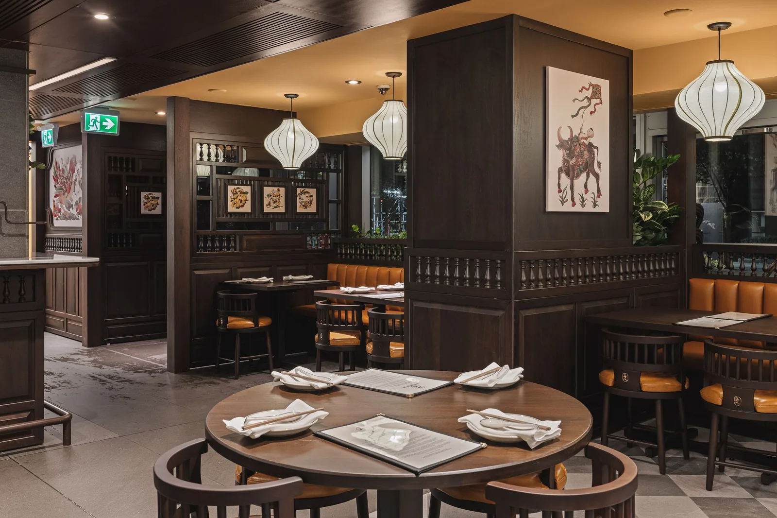 Round table by a wood column with a framed print and lanterns, Linh Noodle Bar by Costar Construction, Vancouver