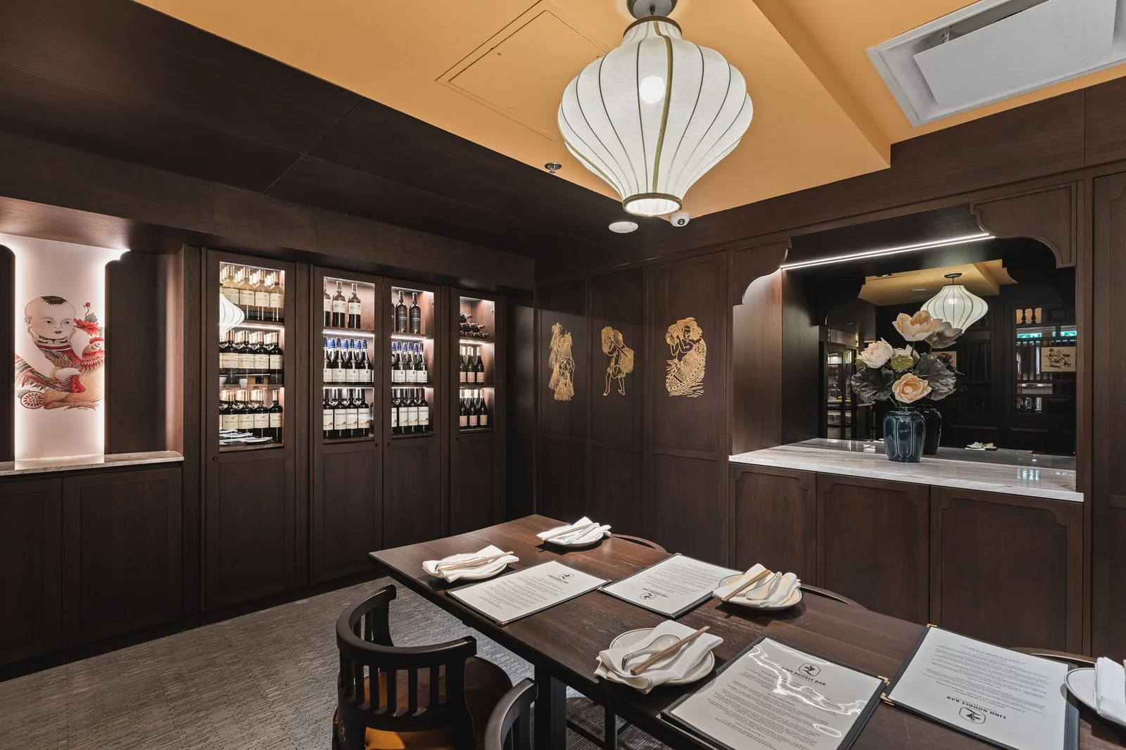 Private dining table beside wine cabinets and gold figures on the wall, Linh Noodle Bar by Costar Construction, Vancouver