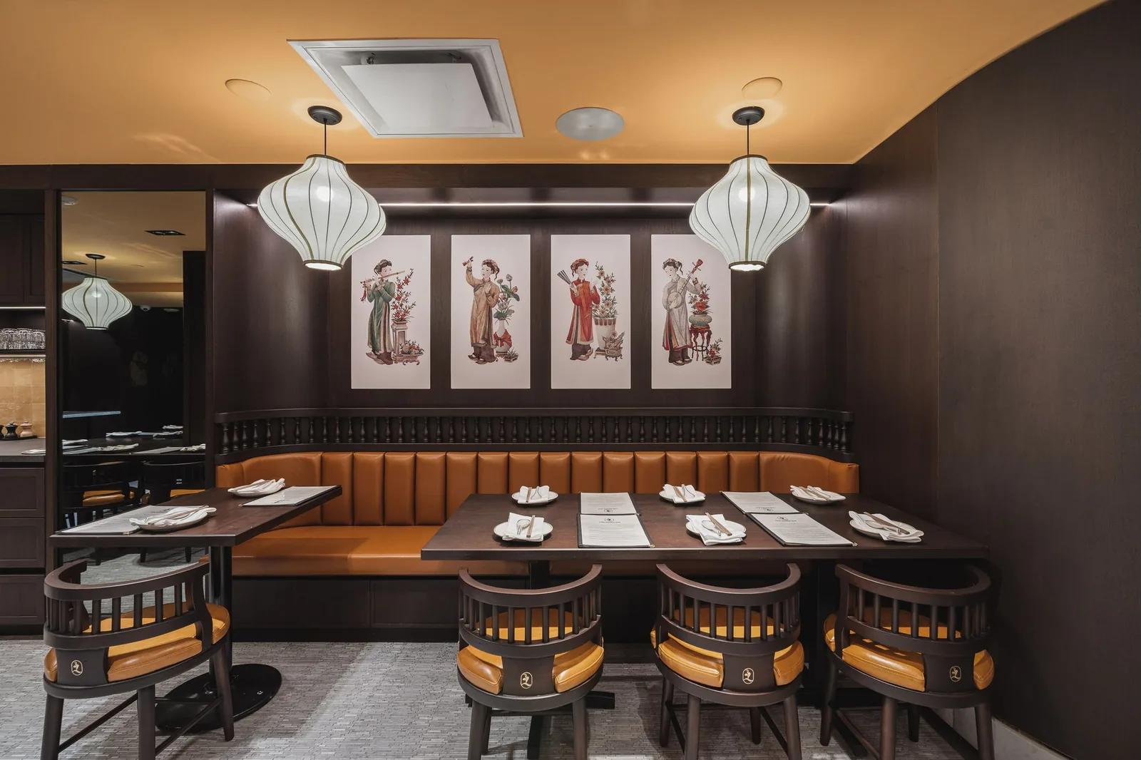 Booth and tables below four framed prints and two lanterns, Linh Noodle Bar by Costar Construction, Vancouver