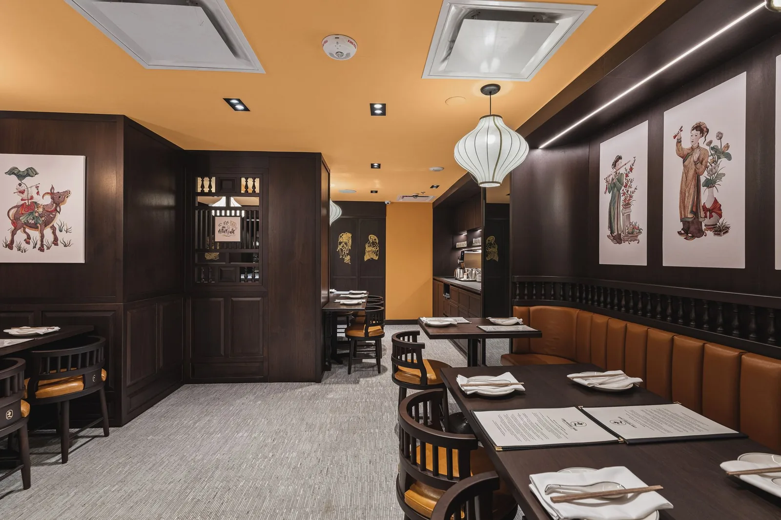 Booth and tables by dark wood walls with framed prints, Linh Noodle Bar by Costar Construction, Vancouver