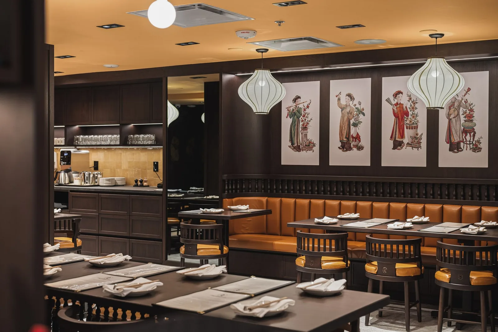 Tables and a booth below four framed prints and lanterns, Linh Noodle Bar by Costar Construction, Vancouver