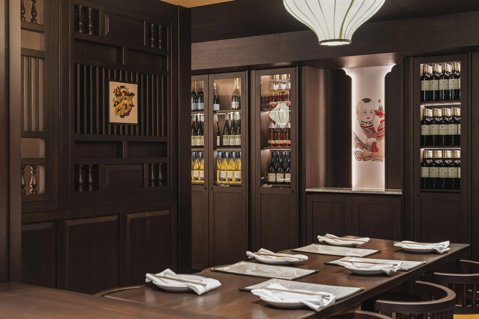 Table near wine cabinets and a lit painted column, Linh Noodle Bar by Costar Construction, Vancouver