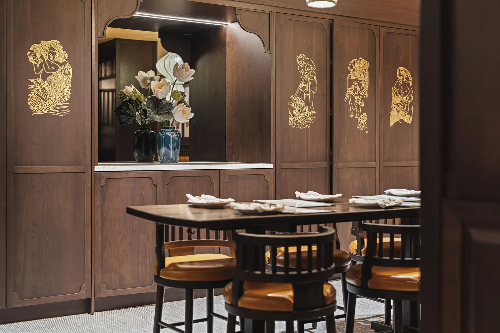 High table with stools in front of gold figures on wood panels, Linh Noodle Bar by Costar Construction, Vancouver