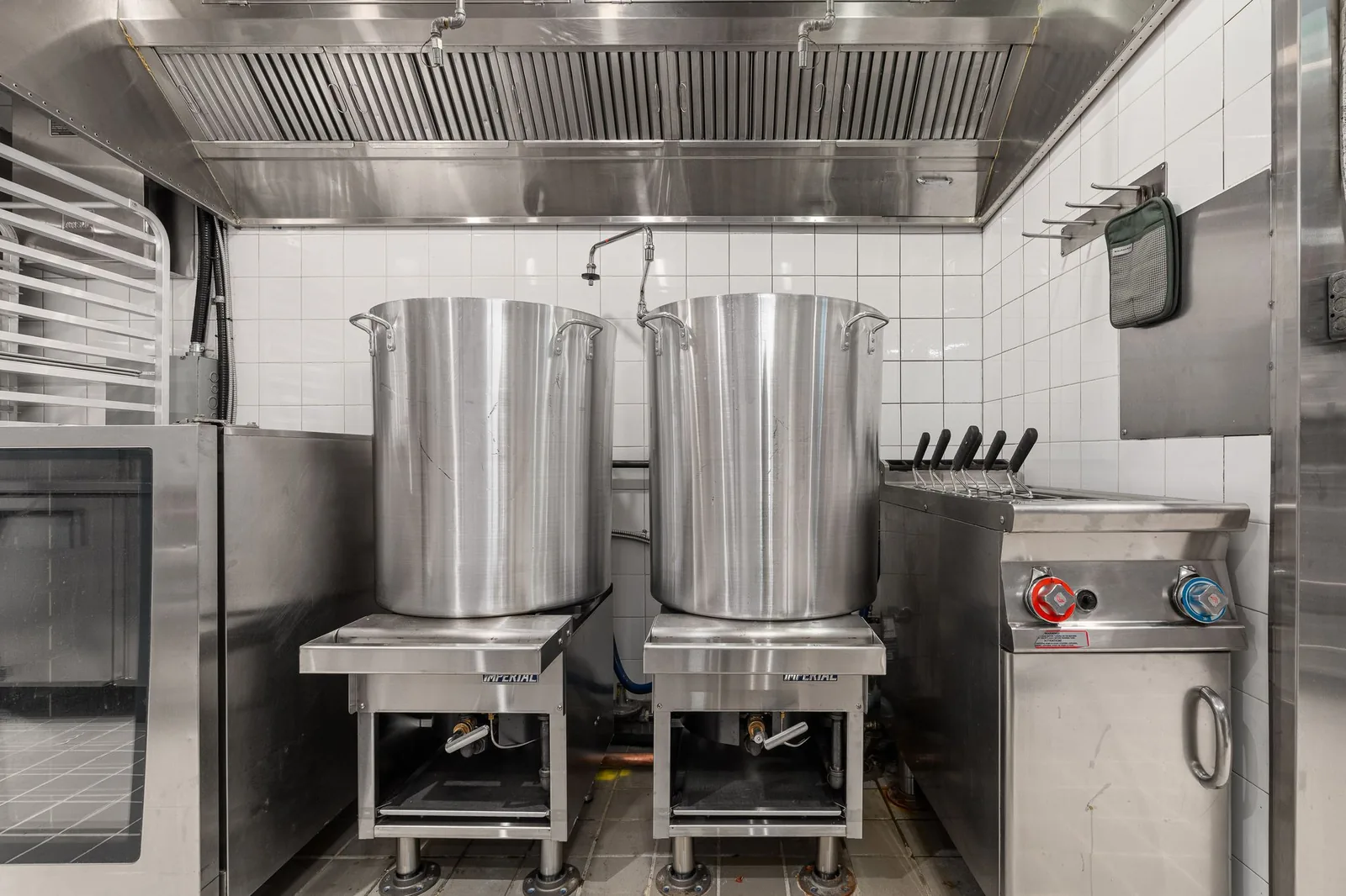 Two stock pots on burners beside a fryer under the hood, Linh Noodle Bar by Costar Construction, Vancouver