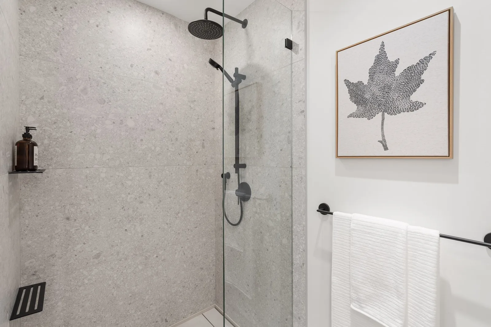 Ensuite with a walk-in shower, floating vanity and matte black fixtures in the Quintet show home