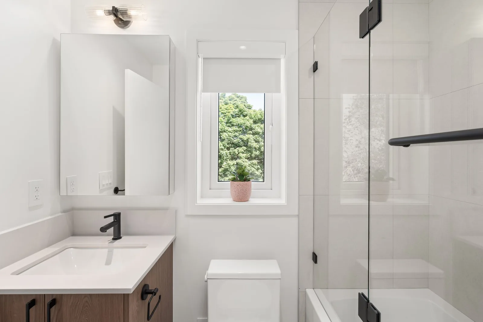 Main bathroom with a soaker tub, glass screen and black fixtures in the Quintet show home