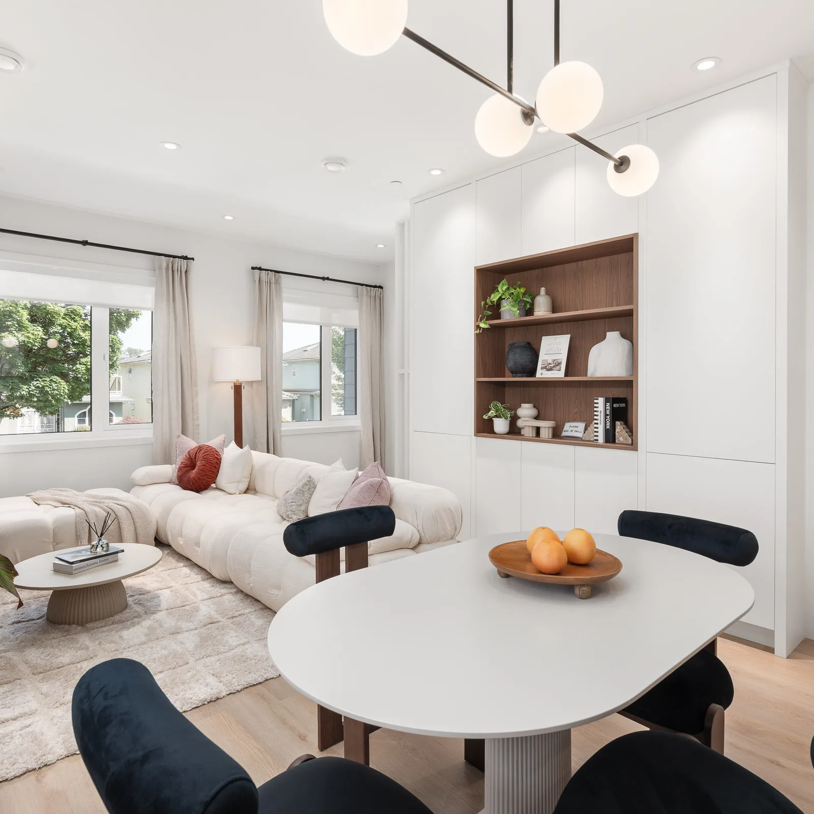 Dining table and sofa in the Quintet show home, with built-in white cabinets and a walnut display niche