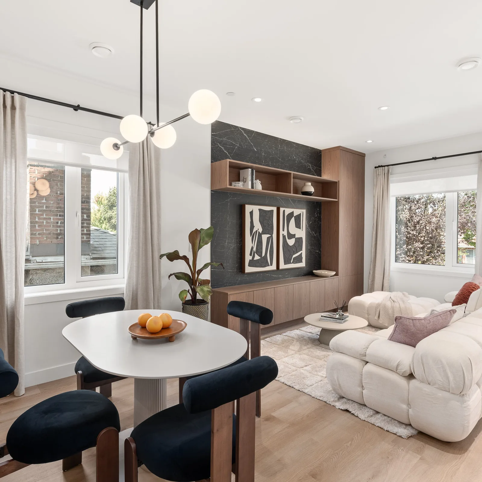 Living room of the Quintet show home seen from the dining table, with the stone entertainment wall and a street window