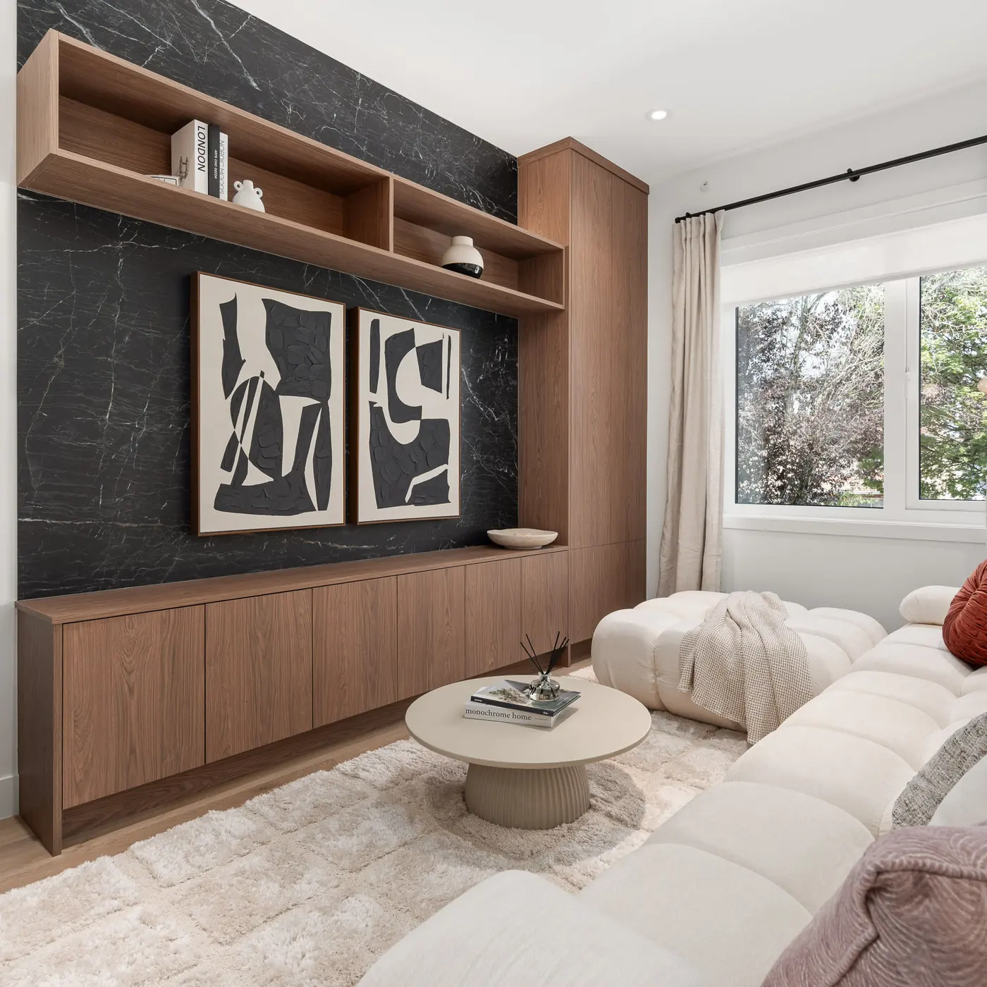Built-in entertainment unit with walnut shelves and a black stone wall in the Quintet show home
